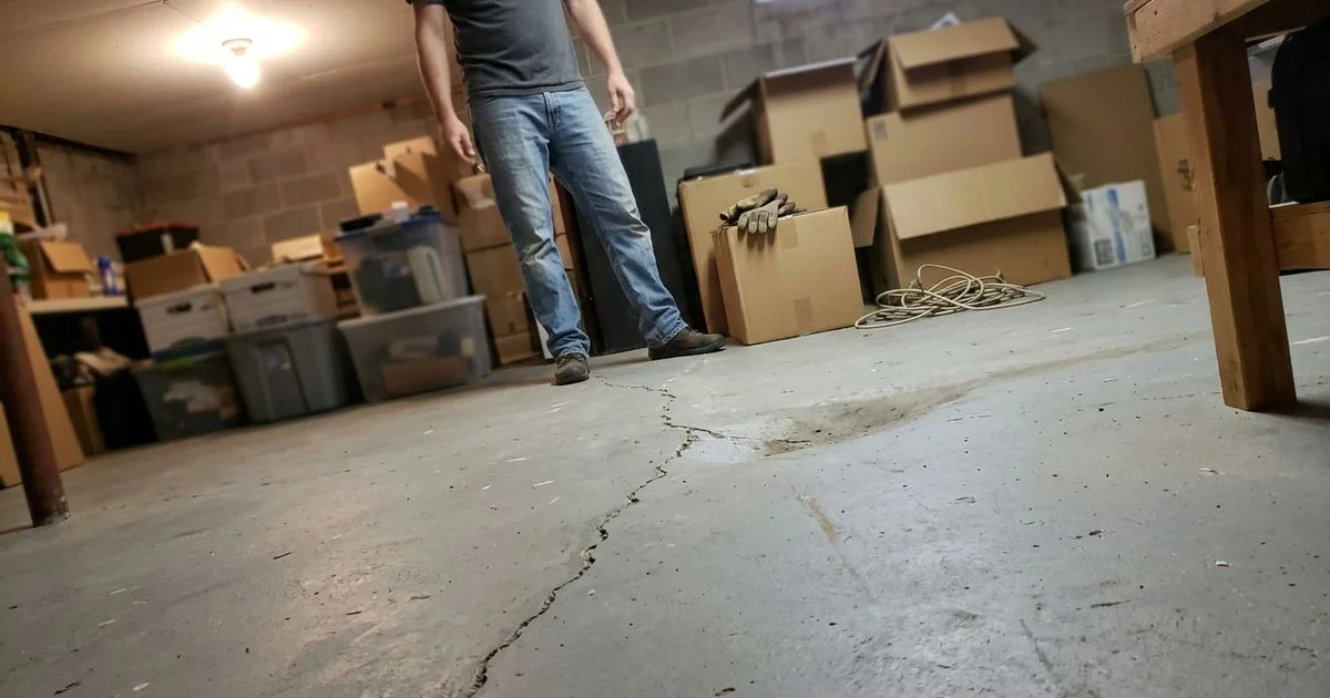 Basement floor with a visible dip and crack running along an old plumbing trench line
