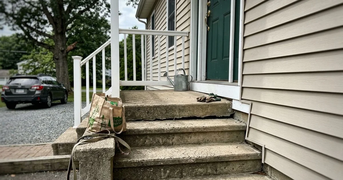 Concrete front steps with a visible gap where they have pulled away from the house wall