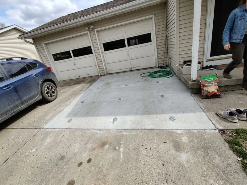 The same driveway lifted flush to the garage slab with patched injection ports
