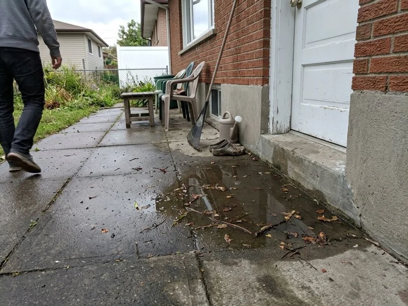 Backyard patio tilting toward the house with water standing against the foundation