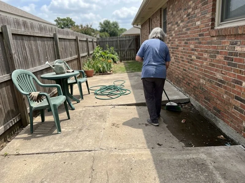Backyard concrete patio tilting toward the house with water standing against the foundation