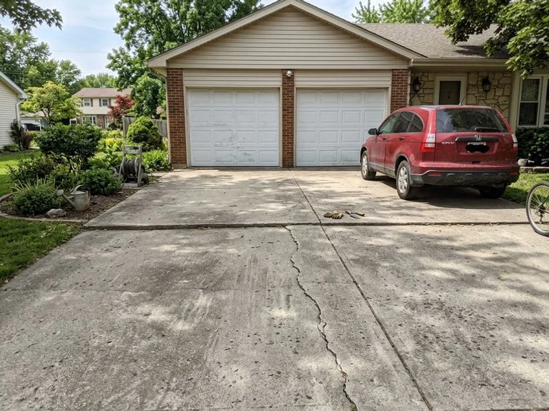 Settled two-car driveway with a visible step down at the garage apron before lifting