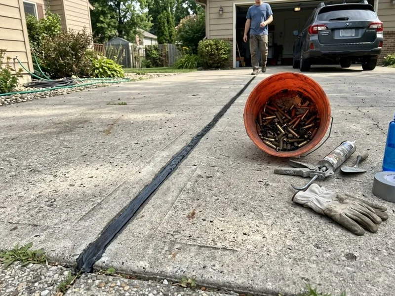 Freshly sealed control joint running the length of a driveway with a tooled finish