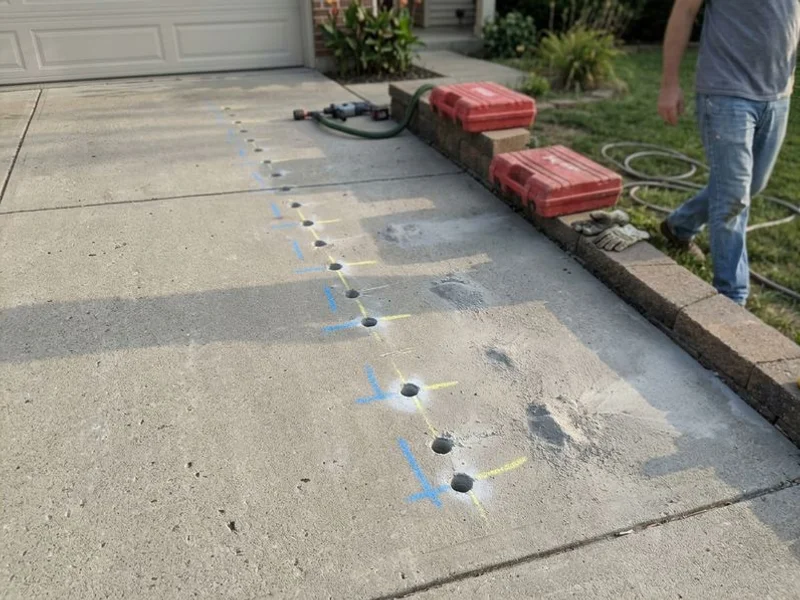 Injection ports drilled across a driveway slab in a planned grid pattern