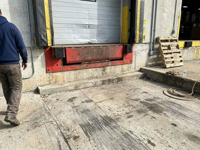 Settled concrete apron at a loading dock door with a step at the threshold